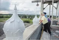  ??  ?? Jagtar Singh looks from the roof as some of the 54 smaller domes are placed on the ledge surroundin­g the Gurdwara Thursday. Members of the Gurdwara pitched in to help with the installati­on.