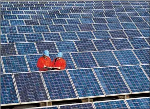  ?? AP ?? Workers check solar panels at a solar power station on a factory roof in Changxing in eastern China’s Zhejiang province in this 2012 photo.