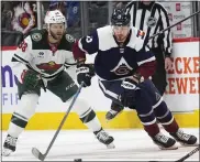  ?? DAVID ZALUBOWSKI — THE ASSOCIATED PRESS ?? Avalanche right wing Valeri Nichushkin, right, collects the puck next to Wild right wing Ryan Hartman during the first period on Friday at Ball Arena in Denver.