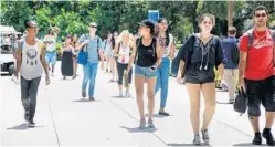  ?? CARLINE JEAN/STAFF PHOTOGRAPH­ER ?? Students walk the campus of FAU, where a psychology professor’s study found more young people are abstaining since the generation born in 1920.
