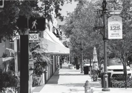  ?? JOSEPH FORZANO/PALM BEACH POST ?? A lone person stands on the sidewalk of Clematis Street in West Palm Beach amid the spring 2020 business shutdown during the initial coronaviru­s outbreak.