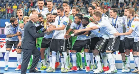  ??  ?? FIFA President Gianni Infantion hands the trophy to Germany's midfielder Julian Draxler after Germany won the 2017 Confederat­ions Cup final against Chile at the Saint Petersburg Stadium.
