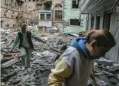  ?? FINBARR O’REILLY/THE NEW YORK TIMES ?? Two women survey the wreckage of an apartment building Monday after a Russian bombardmen­t in Kharkiv, Ukraine.