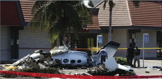  ??  ?? Investigat­ors survey the wreckage of a twin-engine aircraft that crashed on Sunday near the South Coast Plaza center on Monday, in Santa Ana. All five people aboard the plane were killed. AP PHOTO/JAE C. HONG