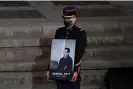  ?? Photograph: François Mori/AP ?? A Republican Guard holds a portrait of Samuel Paty in the courtyard of Paris’s Sorbonne university during a national memorial event in 2020.