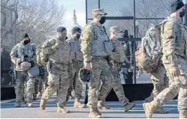  ?? JACQUELYN MARTIN/AP ?? Members of the National Guard change shifts as they exit through anti-scaling security fencing Saturday in Washington ahead of the inaugurati­on Wednesday.