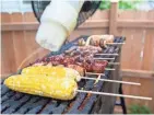  ?? TYGER WILLIAMS, MILWAUKEE JOURNAL SENTINEL ?? Abby Kazal-Thresher, a cook for the Iron Grate BBQ food truck, oils the food on the yakitori-style grill. The food cooks over fire fed by wood.