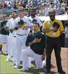  ??  ?? Oakland Athletics’ Mark Canha places his hand on the shoulder of Bruce Maxwell as Maxwell takes a knee during the national anthem prior to a baseball game against the Texas Rangers, Sunday, in Oakland. AP PHOTO/BEN MARGOT