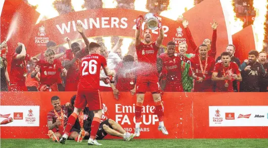  ?? PHOTOS: REUTERS ?? I see red . . . Liverpool captain Jordan Henderson lifts the silverware after his side beat Chelsea 65 on penalties in the FA Cup final at Wembley in London yesterday. Right: Liverpool manager Juergen Klopp reacts at the end of the shootout.