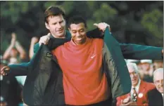  ?? AP file photo ?? Tiger Woods receives his Green Jacket from previous year’s winner Nick Faldo, on April 13, 1997. Woods became the youngest, at 21, to win at Augusta.