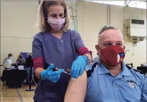  ?? Erik Trautmann / Hearst Connecticu­t Media ?? Tokeneke School nurse Kim Martini administer­s the shot to Darien High School french teacher Bruce Mitchell as teachers get vaccinated against the coronaviru­s on March 6 at Town Hall in Darien.