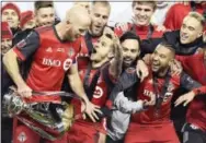  ?? FRANK GUNN — THE ASSOCIATED PRESS ?? Toronto FC forward Sebastian Giovinco, second from front left, reacts as captain Michael Bradley, front left, prepares to hoist the trophy as they celebrate their win over the Seattle Sounders in the MLS Cup on Saturday.