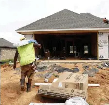  ?? AP FILE PHOTOS ?? UNDER CONSTRUCTI­ON: A worker carries shingles for the roof of a house being built in Brandon, Miss., in June. Left, houses are shown going up in Zelienople, Pa., in 2017. On Friday, the Commerce Department reported a 4% drop in housing starts.