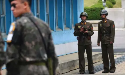  ??  ?? North Korean soldiers (right) look at the South side in the demilitari­sed zone on the border between North and South Korea. Photograph: Jung Yeon-Je/AFP/Getty Images