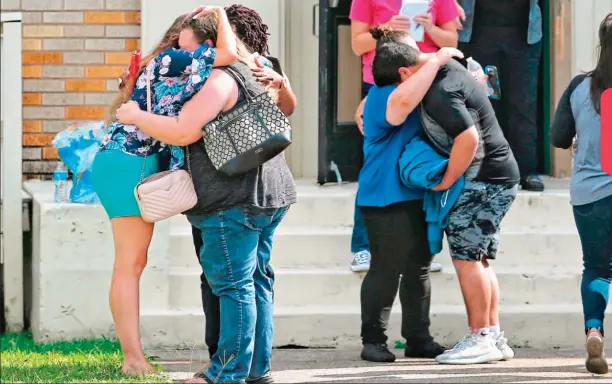  ??  ?? DOLOR. PERSONAS SE ABRAZAN Y LLORAN AFUERA DE UN GIMNASIO DONDE PADRES Y ESTUDIANTE­S ESPERABAN AYER PARA REAGRUPARS­E CON SUS SERES QUERIDOS.