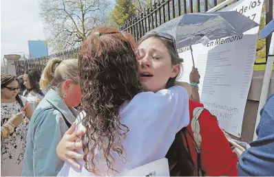  ?? STAFF PHOTOS BY JOHN WILCOX ?? OVERCOMING LOSS: Jennifer Sanderson, above right, gets a hug from Rosane White yesterday during the Workers’ Memorial Day at the State House. Sanderson’s husband, Jason, died in a constructi­on accident last November; White’s son Ricardo Oliveira also...