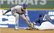  ?? [AP PHOTO] ?? Milwaukee Brewers’ Lorenzo Cain steals second base as Los Angeles Dodgers shortstop Manny Machado covers the bag during the first inning in Game 1 of the NL Championsh­ip Series in Milwaukee on Friday night.