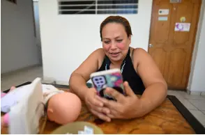  ?? ?? Alba Lorena Rodriguez, a member of ‘Las 17 y Mas,’ a group of women who were convicted after facing obstetric emergencie­s with sentences of up to 50 years in prison and charged with aggravated homicide, looks at her cell phone after an interview with AFP in San Salvador.
