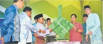  ??  ?? Dr Annuar (third left) cuts the ribbon on the giant ‘ketupat’ to mark the start of Raya festivitie­s at Lakis Hall. Looking on from right are Wan Hamid, Saiful Bahri and Chang Kee.