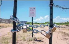  ??  ?? A road on Cochiti Pueblo land that runs along the Santa Fe River near the village of La Bajada has been closed by the pueblo. Residents of La Bajada, who say they have legal right of way to the land, put up their own signs past the pueblo fence.