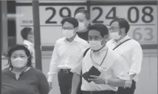  ?? ?? TOKYO
People walk by an electronic stock board of a securities firm in Tokyo.
-AFP