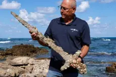  ?? Jack Guez, Afp/getty Images ?? At a beach in the Israeli seaport of Caesarea, Jacob Sharvit of the Israel Antiquitie­s Authority displays an ancient sword that experts say dates to the Crusades.