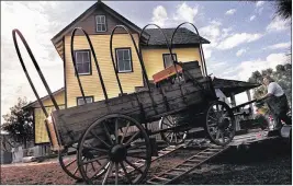  ?? PALM BEACH POST 1999 ?? Yesteryear Village at the South Florida Fairground­s boasts a collection of historical buildings such as the Riddle House, seen in the background as Kim Belvin unloads his replica 1890s butcher’s wagon ahead of the 2000 South Florida Fair.