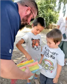  ?? Dan Watson/The Signal ?? (Above) Castaic Union School District Superinten­dent Steve Doyle, left, lets Itsuki Trexel, 6, and Akira Trexel pick out ice pops during the Castaic Welcome Wagon tour. (Below) Youth run toward the Castaic Welcome Wagon to get frozen treats.
