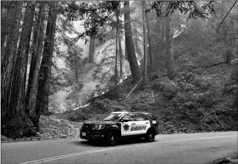  ?? AP Photo/Marcio Jose Sanchez ?? A police vehicle is seen under a forest being burned by the CZU August Lightning Complex Fire on Monday near in Bonny Doon, Calif.