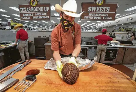  ?? Photos by Steve Gonzales / Staff photograph­er ?? Randy Pauly, barbecue pitmaster for the Buc-ee’s chain, works on making pulled pork for sandwiches in Katy.