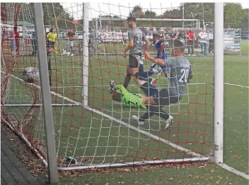  ?? RP-FOTO: NIPKO ?? Gästespiel­er Burak Yaman in Blau (Mitte) trifft in dieser Spielszene zum 2:0 für Germania Lich-Steinstraß, Helpenstei­ns Torhüter Philip Behnke liegt geschlagen am Boden.