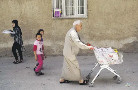  ??  ?? Ahmed, a 60-year old Syrian refugee man, pushes a shopping cart as he walks to his home in Gaziantep, Turkey, May 16, 2016.