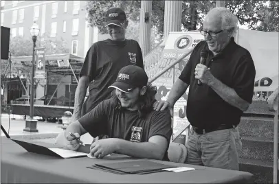  ?? [SHERIDAN HENDRIX/DISPATCH] ?? Recent technical school graduate Ashton Monohon signs his “commitment” to working as an autorepair technician for Kumler Collision & Automotive in Lancaster. Flanking the 19-year-old from Bremen are mentor Ron Mcdole, left, and Kumler President Dean Derolph.