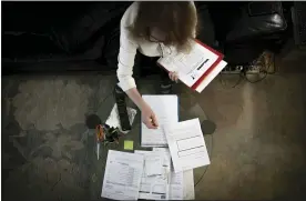  ?? ROBERT BUMSTED — THE ASSOCIATED PRESS ?? Bonney Ginett sifts through paperwork for her applicatio­n to a federally-funded program to help pay back rent, March 18, in the Queens borough of New York.