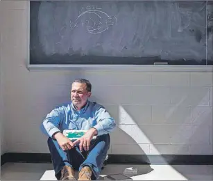  ?? CP PHOTO ?? Math teacher Paul Alves holds a visual learning aid as he sits below a traditiona­l math equation on a classroom’s chalk board at Fletcher’s Meadow Secondary School in Brampton, Ont., on Wednesday.