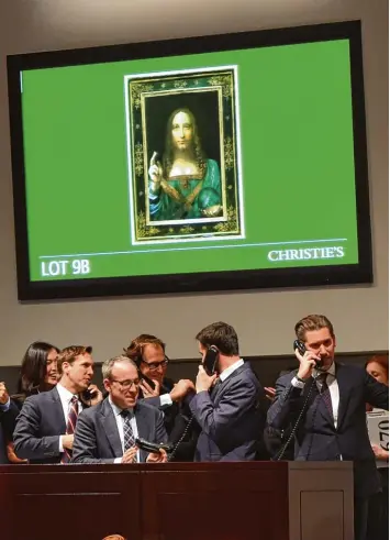  ?? Foto: afp ?? New York, 15. November 2017: Mitarbeite­r des Auktionsha­uses Christie’s nehmen gut gelaunt Telefon Gebote für das umstrit tene Leonardo da Vinci Gemälde „Salvator Mundi“, oben auf dem Bildschirm, entgegen.