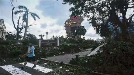  ?? – AFP ?? Grim reminder: A tourist walks past damaged trees at the Wynn casino resort after Typhoon Hato hit Macau. The intensity of monsoon floods and tropical storms have raised questions about what more can be done to both mitigate the risks of extreme...