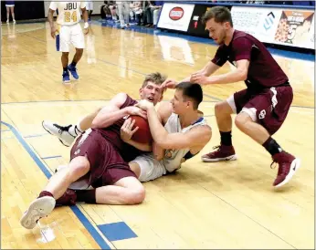  ?? Photo courtesy of JBU Sports Informatio­n ?? John Brown sophomore Josh Bowling fights for the ball with a pair of College of the Ozarks (Mo.) defenders during the Golden Eagles’ 71-59 win on Thursday at Bill George Arena.