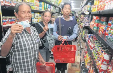  ??  ?? Low-income earners show their state welfare cards while shopping for food and other necessitie­s at a store where the cards are accepted.