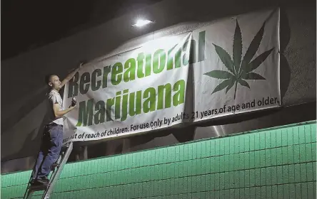  ?? AP FILE PHOTOS ?? RUSH JOB: A banner for a marijuana dispensary is hung in Las Vegas, where pot was legalized and available for sale in a much shorter time than the Bay State is taking.