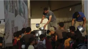  ?? KHALIL ASHAWI/REUTERS PHOTOS ?? Syrians scramble for food in northern Aleppo. Activists say the government is trying to cut off city’s water supply.