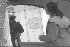  ?? AP ?? Commuters pass a Wells Fargo ATM in New York’s Penn Station in this file photo. Wells Fargo said Friday that it earned $4.6 billion in the third quarter.