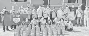  ??  ?? BANTU: Ting (tengah) menyampaik­an alat pemadam api kepada penduduk Sungai Pinang.