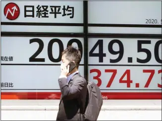  ??  ?? A man wearing a face mask to help curb the spread of the coronaviru­s walks past an electronic stock board showing Japan’s Nikkei 225 index at a securities firm in Tokyo Friday, May 8. Asian shares surged Friday on optimism the worst of the economic fallout from the pandemic may be over, as Wall Street logged its biggest rally in a week.
(AP)