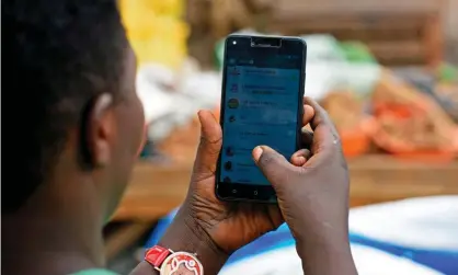  ??  ?? A woman in Kampala scrolls through her WhatsApp messages. Critics say Uganda’s social media tax is a restraint on free speech. Photograph: Isaac Kasamani/AFP/Getty Images