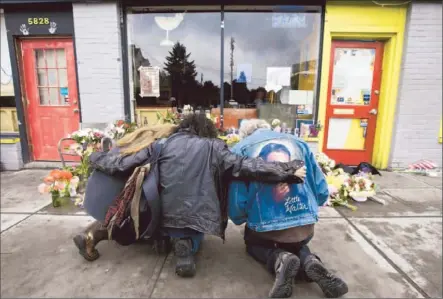  ?? Stephen Brashear Getty Images ?? OUTSIDE SEATTLE’S Cafe Racer, where four people were shot dead and a fifth was critically wounded, residents visit a makeshift memorial a day after the violence. Citywide, 21 people have died in gun violence since the start of the year, as many as in...