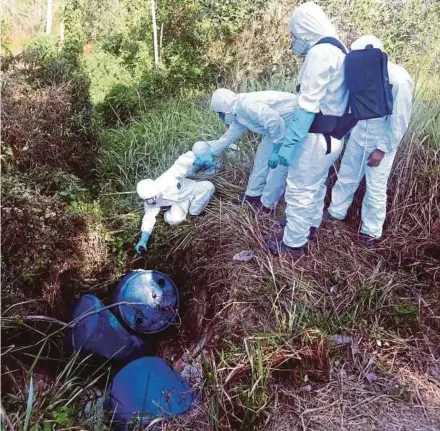  ?? PIC BY HAIRUL ANUAR RAHIM ?? The Fire and Rescue Department’s Hazardous Materials Unit personnel checking barrels found in a drain near SMK Tanjung Puteri Resort in Pasir Gudang yesterday.