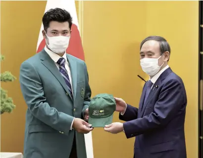  ?? The Yomiuri Shimbun ?? Hideki Matsuyama, left, gives an autographe­d cap to Prime Minister Yoshihide Suga after receiving the Prime Minister’s Award at the Prime Minister’s Office on Friday.