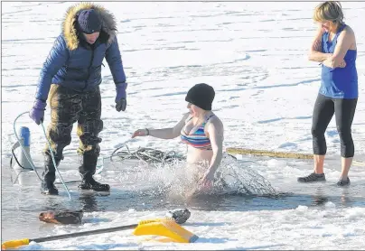  ?? BRIAN MCINNIS/THE GUARDIAN ?? Cheryl Paynter, left, organizer of the polar bear dip, prepares to help a swimmer out of the water after she took the plunge. The swimmers were more than happy to exit the water and get back to shore and into some warm and dry clothes.