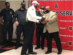  ?? (Special to The Commercial) ?? Firefighte­rs present a large bronze statue of an eagle to the police department in honor of the late Det. Kevin Collins.